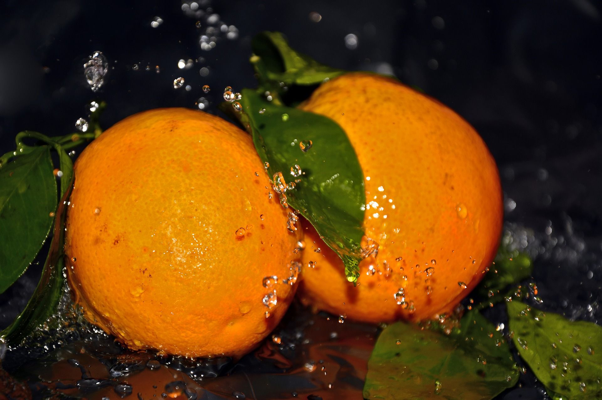 Употребление апельсинов. Сочные фрукты. Сочные фрукты в воде. Сочный апельсин. Апельсин на черном фоне.